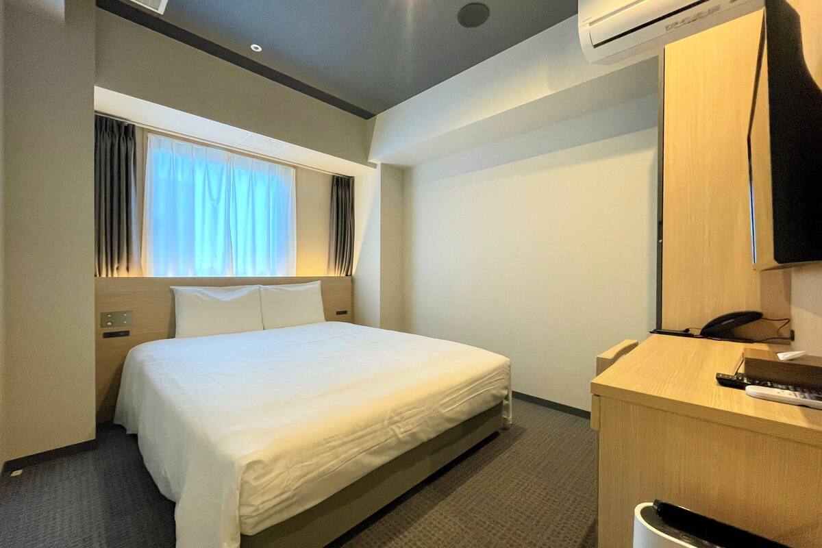 Une chambre d’hôtel équipée d’un lit, d’un bureau, d’une chaise, d’une télévision et d’un appareil de climatisation.