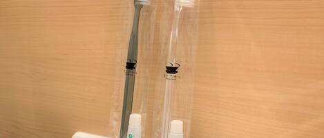 Two toothbrushes and a tube of toothpaste in clear plastic packaging.