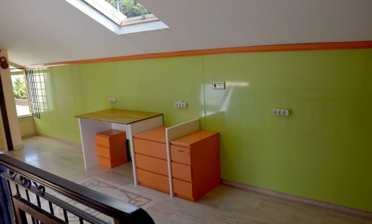 A room with a skylight, green walls, a small desk, and storage units.