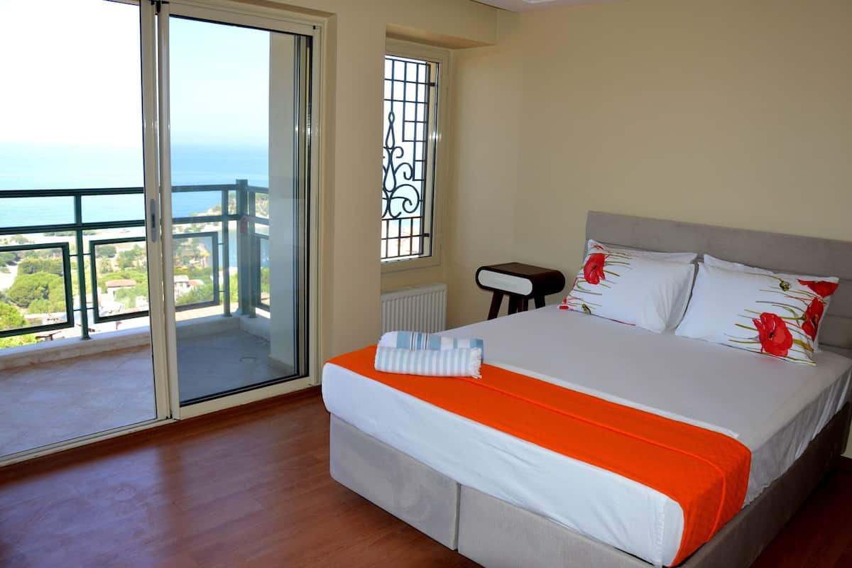A bedroom with a bed, a window with a view, and a balcony.