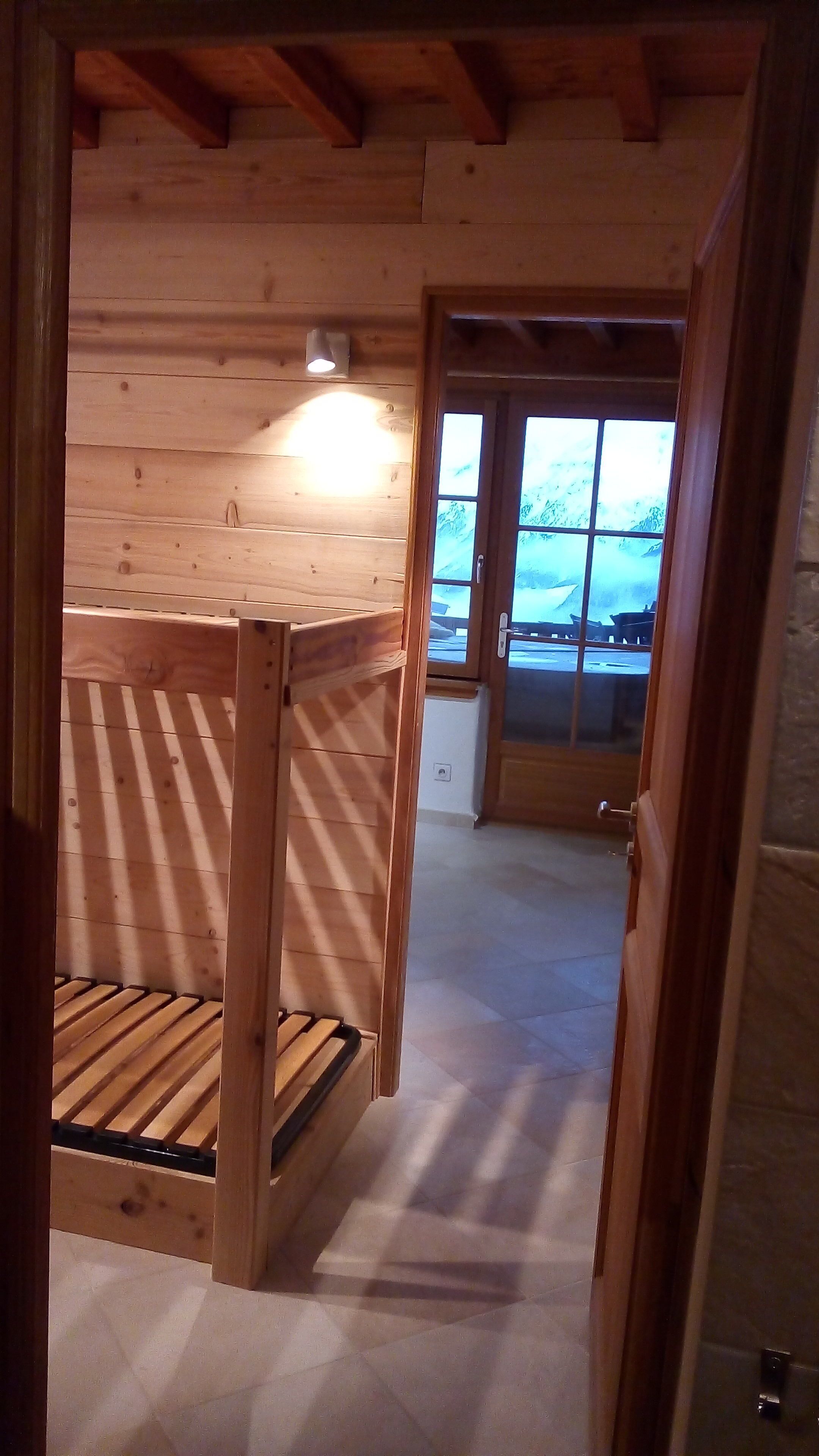 A wooden cabin interior with a bunk bed, a small window, and a door leading outside.