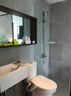A modern bathroom with a large mirror, a toilet, and a shower. - Daun Residence Bandung (Bandung)