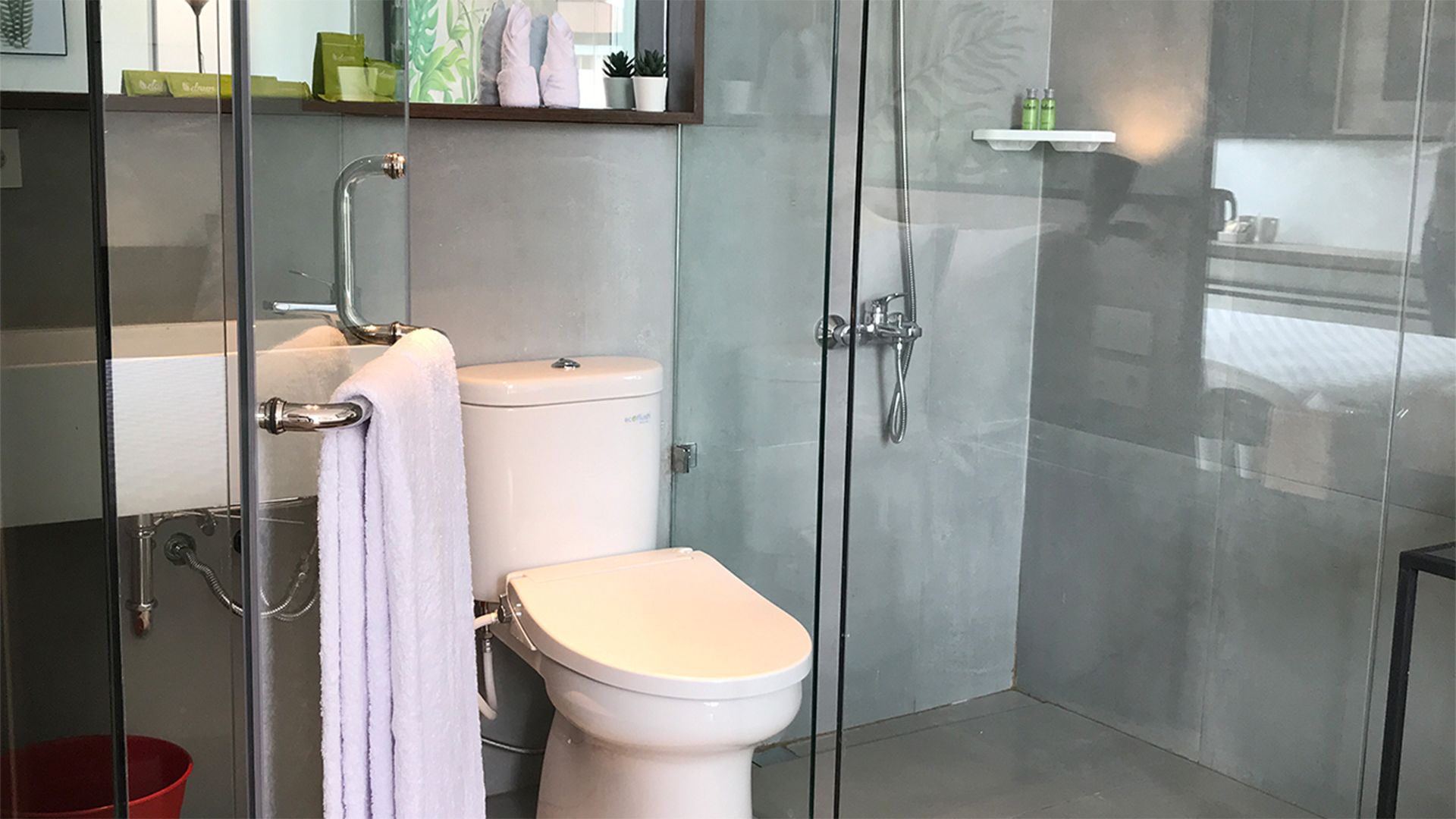 A modern bathroom with a glass shower enclosure, a toilet, and a sink.