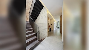 A modern interior with a staircase, a hallway, and a door leading to another room. - Daun Residence Bandung (Bandung)
