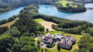 An aerial view of a property with a large building complex, a golf course, and a lake. - Hotel Diehlberg – Tagungs- & Wellnesshotel (Olpe)
