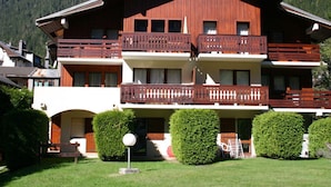 A multi-story hotel with wooden balconies and a mountainous backdrop. - Cozy studio in Chamonix - Pets allowed, private parking (Chamonix-Mont-Blanc)