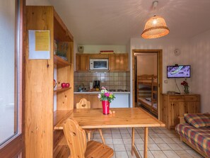 Cozy room with a kitchenette, featuring a dining table, TV, microwave, coffee maker, and bunk bed.