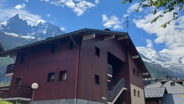 A red building with a balcony and a mountain view. - Cozy studio in Chamonix - Pets allowed, private parking (Chamonix-Mont-Blanc)