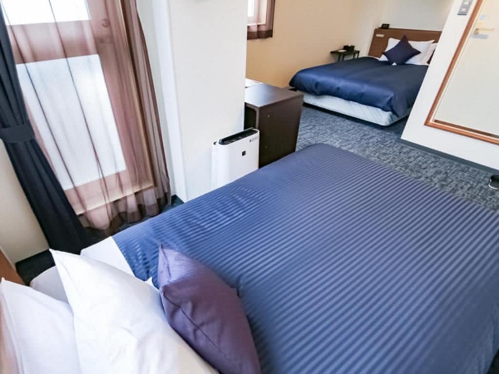 A hotel room with a bed, a desk, and a window with curtains.