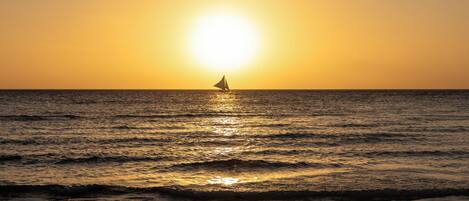 A sailboat on calm waters during sunset.