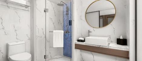 Un baño moderno con ducha envuelta en vidrio, inodoro blanco, suelo de mármol y tocador de madera con lavabo y espejo.