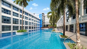 Un hotel moderno con una amplia piscina cubierta, rodeado de palmeras y con un diseño arquitectónico contemporáneo.