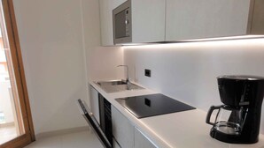Een moderne keuken met een inbouwvaatwasser, een koffiezetapparaat en een magnetron.