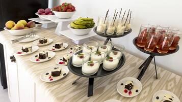 Una mesa de buffet con diversos postres y frutas.