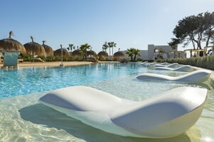 Una piscina al aire libre, sombrillas, tumbonas