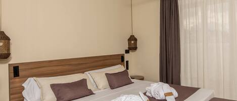 Una habitación de hotel con cama, mesita de noche, ventilador de techo e iluminación colgante.