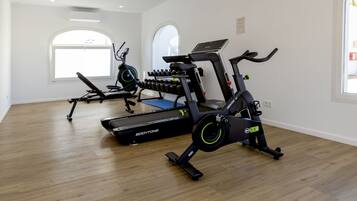 Ein Fitnessstudio mit Cardiogeräten, Krafttrainingsmaschinen und Kurzhanteln.