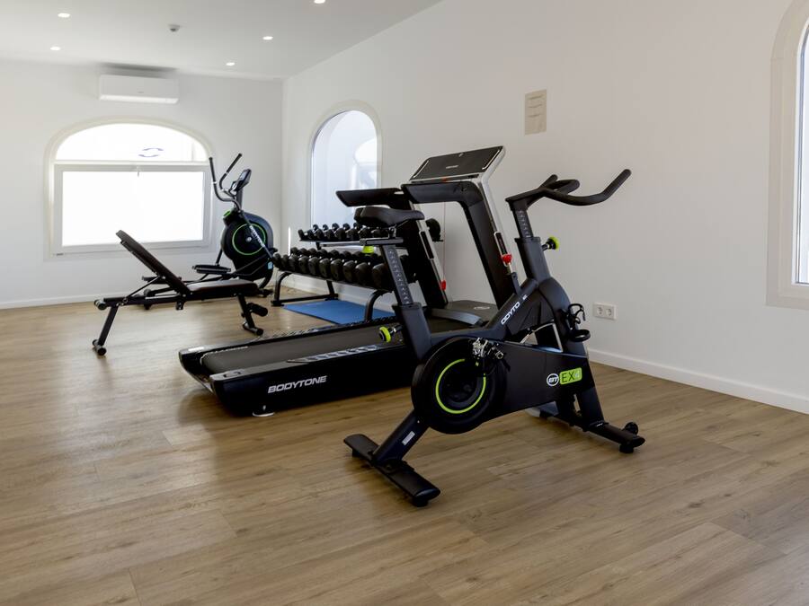 Ein Fitnessstudio mit Cardiogeräten, Krafttrainingsmaschinen und Kurzhanteln.