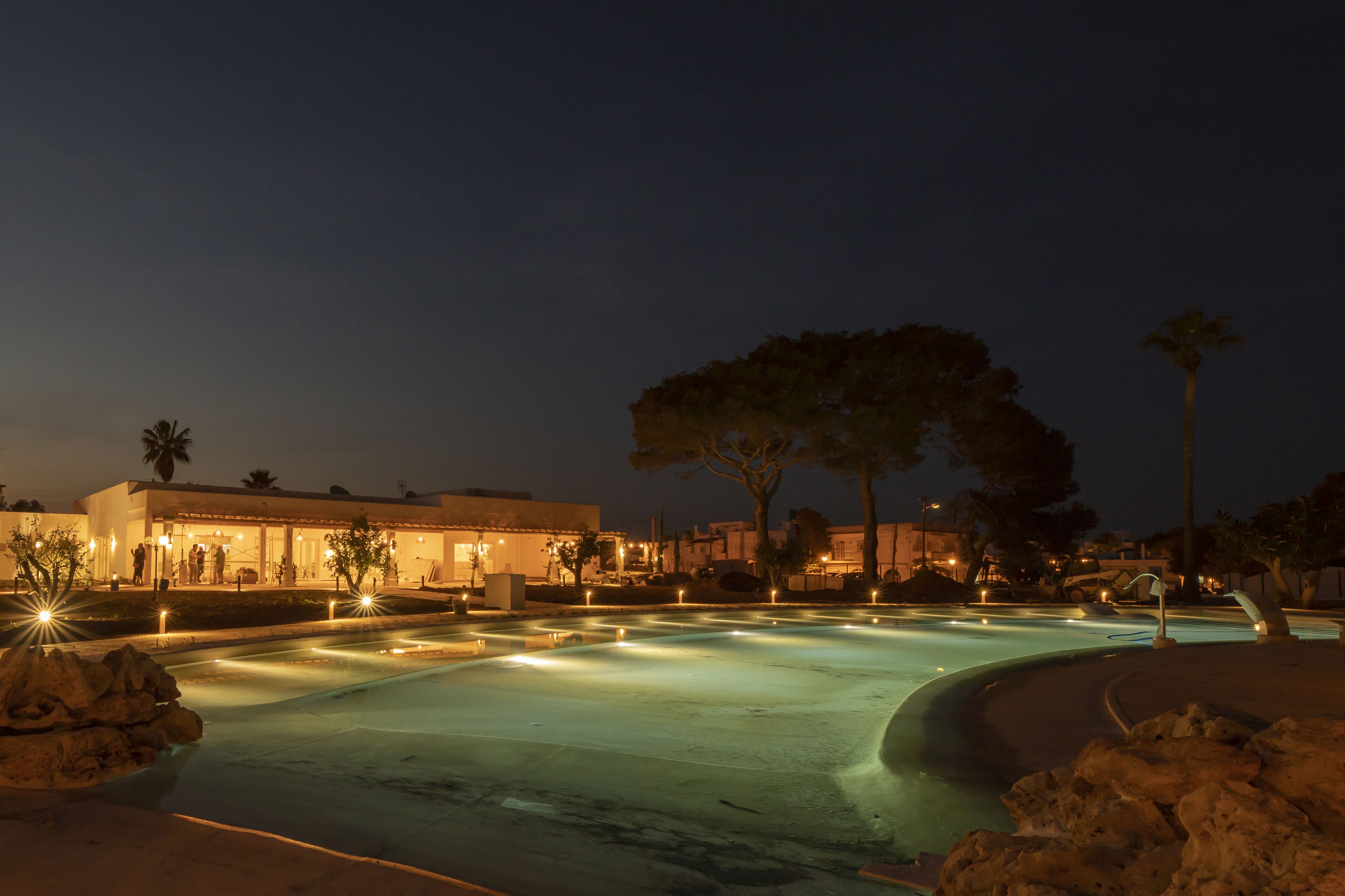 A nighttime view of a swimming pool area with a building in the background.