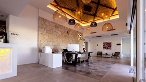 Un área de recepción moderna con pared de piedra, un mostrador de recepción y una zona de estar con alfombra estampada.