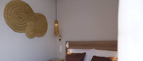 A neatly made bed with a brown bedspread and pillows, a wooden headboard, and a wall-mounted decorative item.