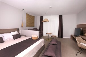 Una habitación de hotel moderna con una cama grande, un escritorio, una silla, un televisor y una mesita.