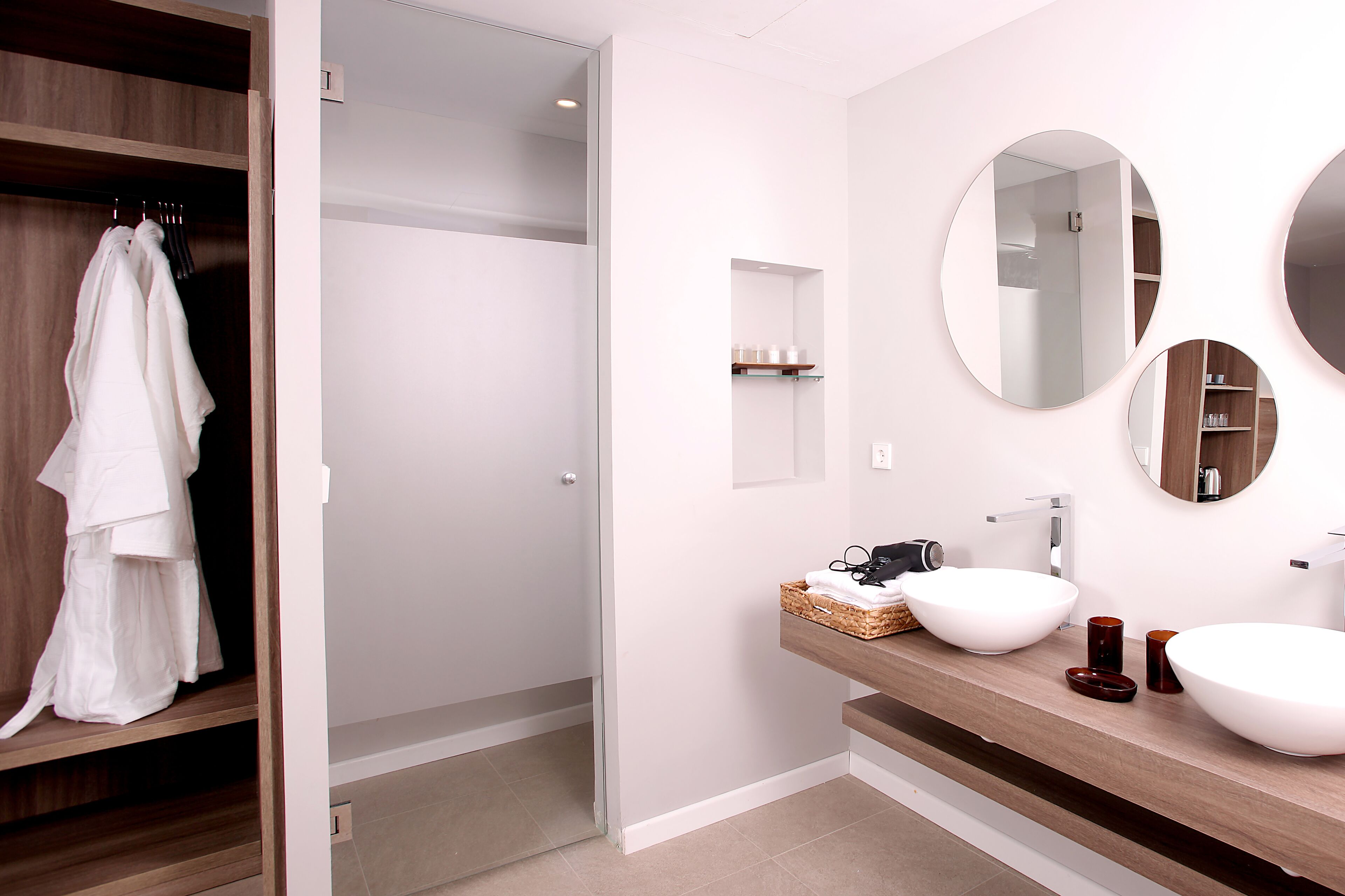 A modern bathroom with a wooden vanity, two large sinks, and a mirror above the vanity.