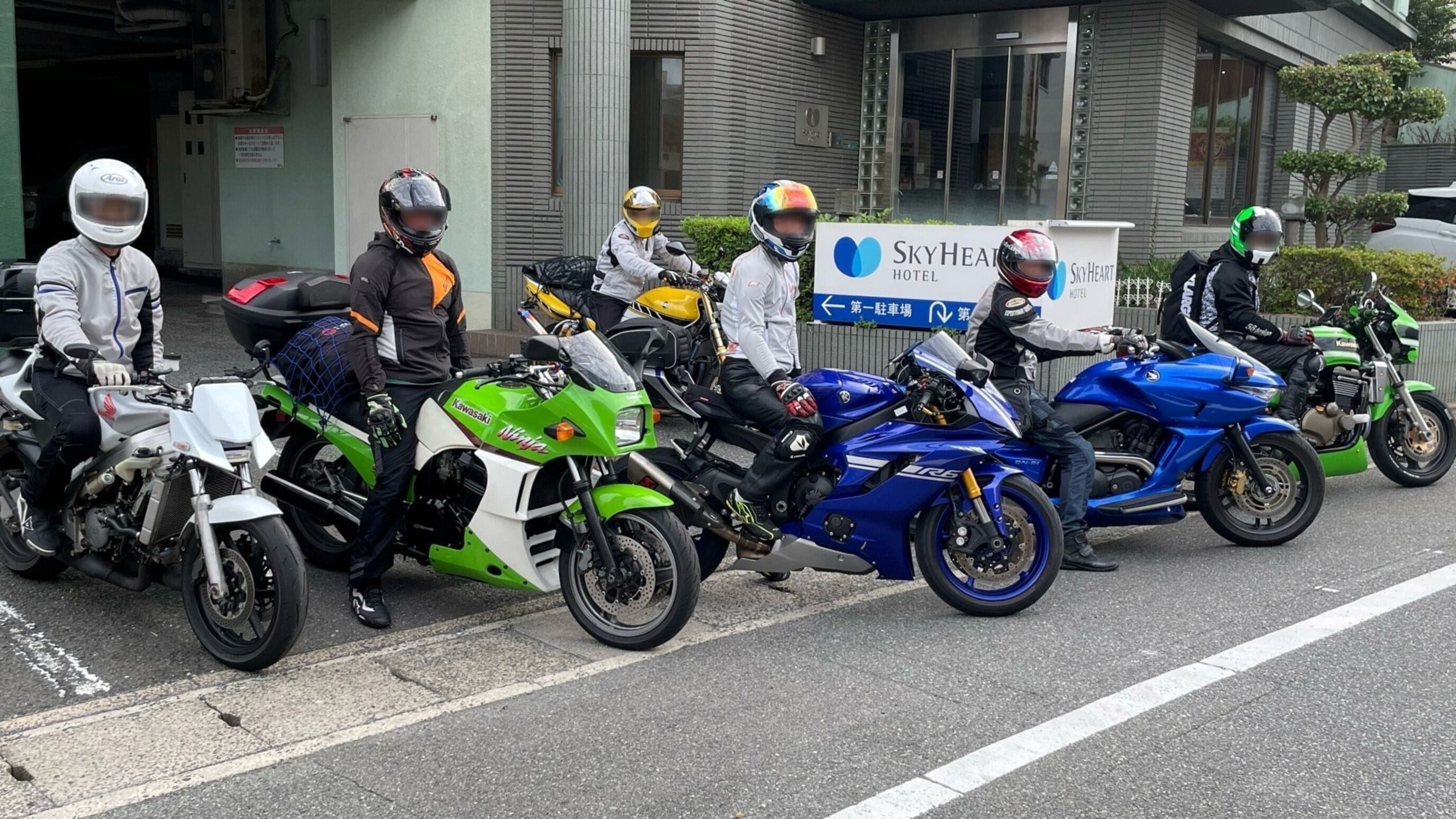 A row of motorcycles parked outside a building with a sign for SkyHeart Hotel.
