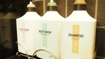 Drei Flaschen Shampoo, Conditioner und Duschgel auf einem Metallgestell.