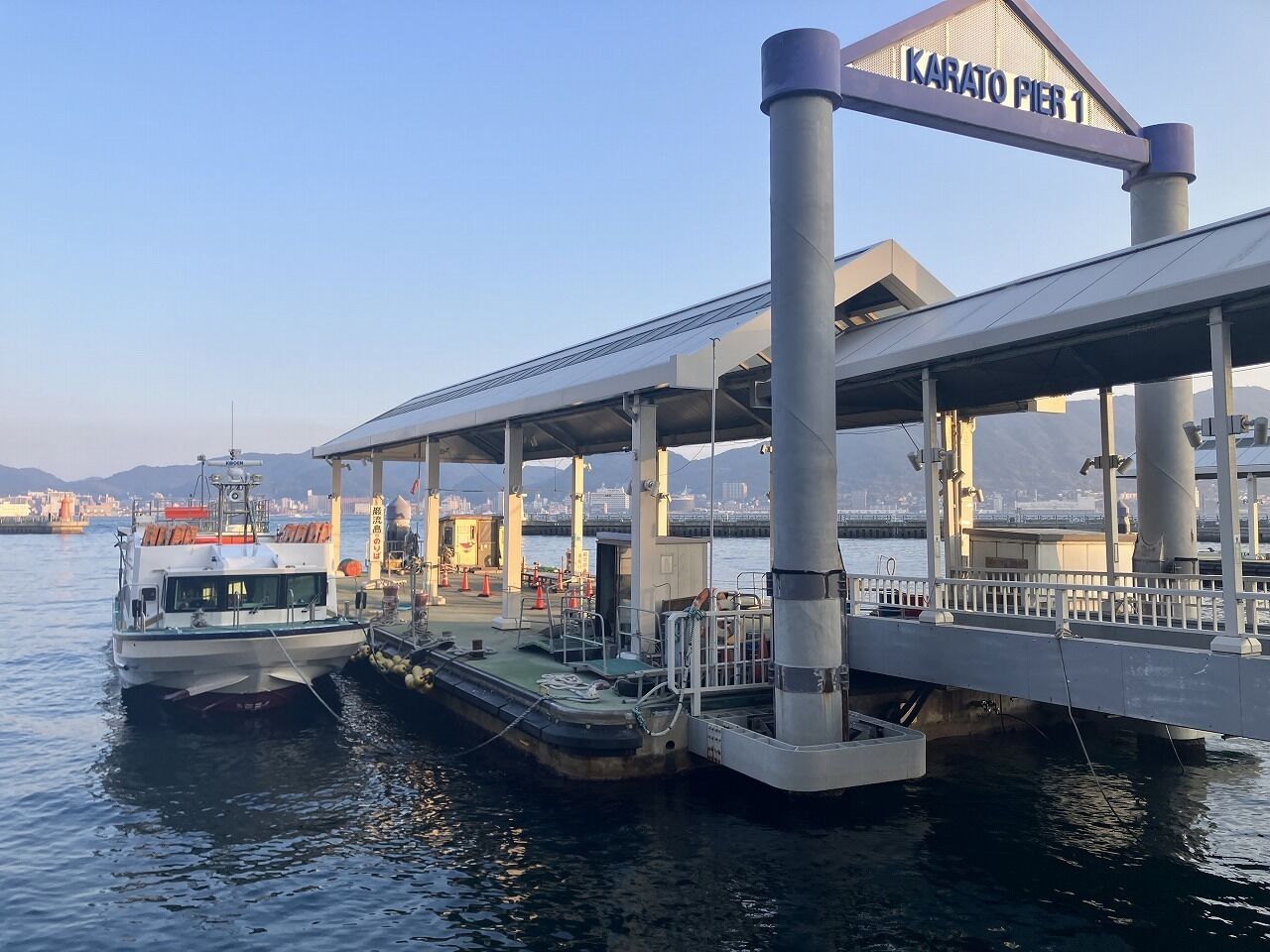 A ferry terminal with a covered pedestrian walkway and a sign reading "Karato Pier 1".