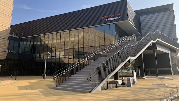Een modern gebouw met een glazen gevel en een trap naar de ingang.