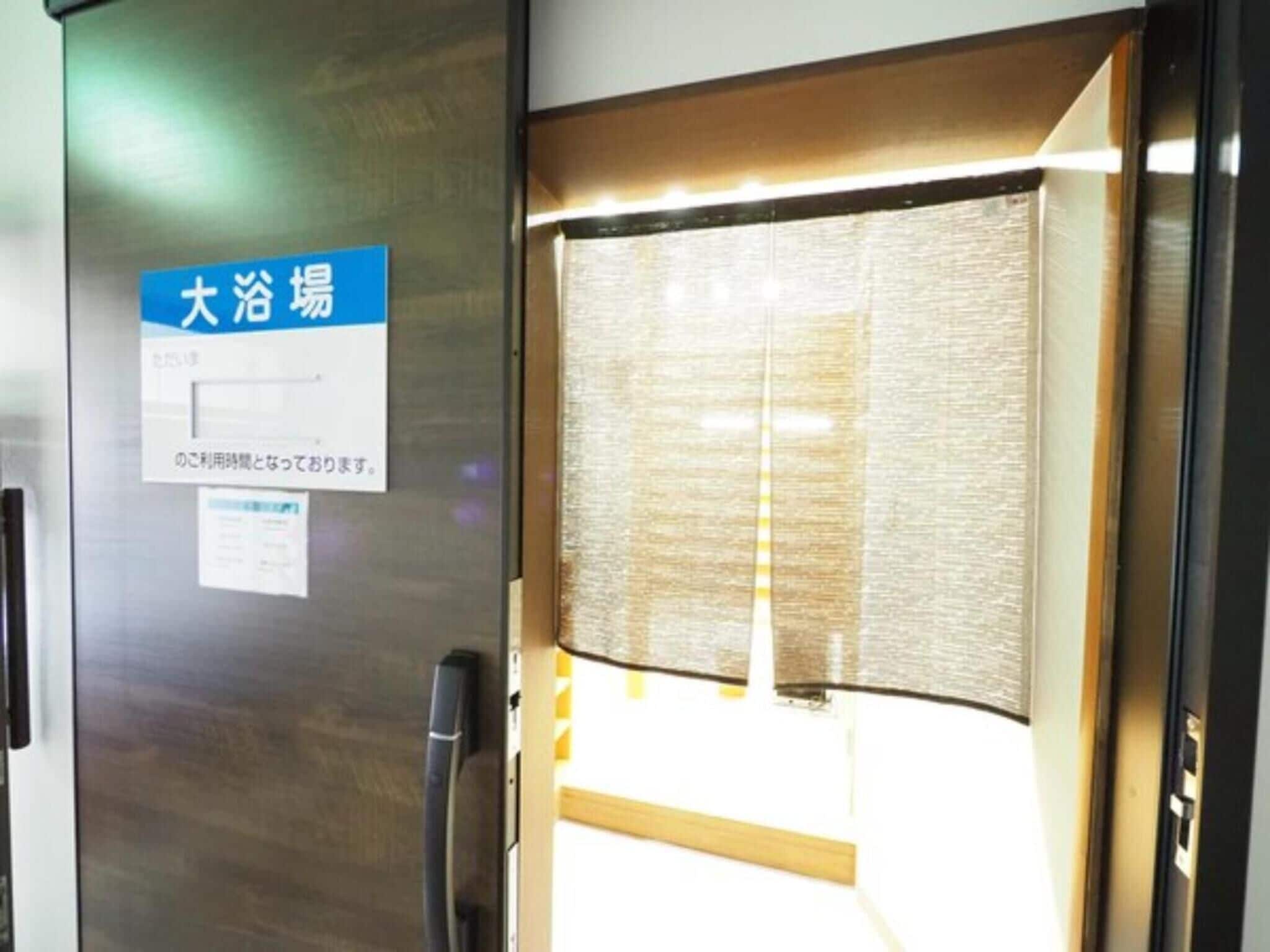 A hotel room entrance with a sliding door, a sign indicating the location, and a window with blinds.