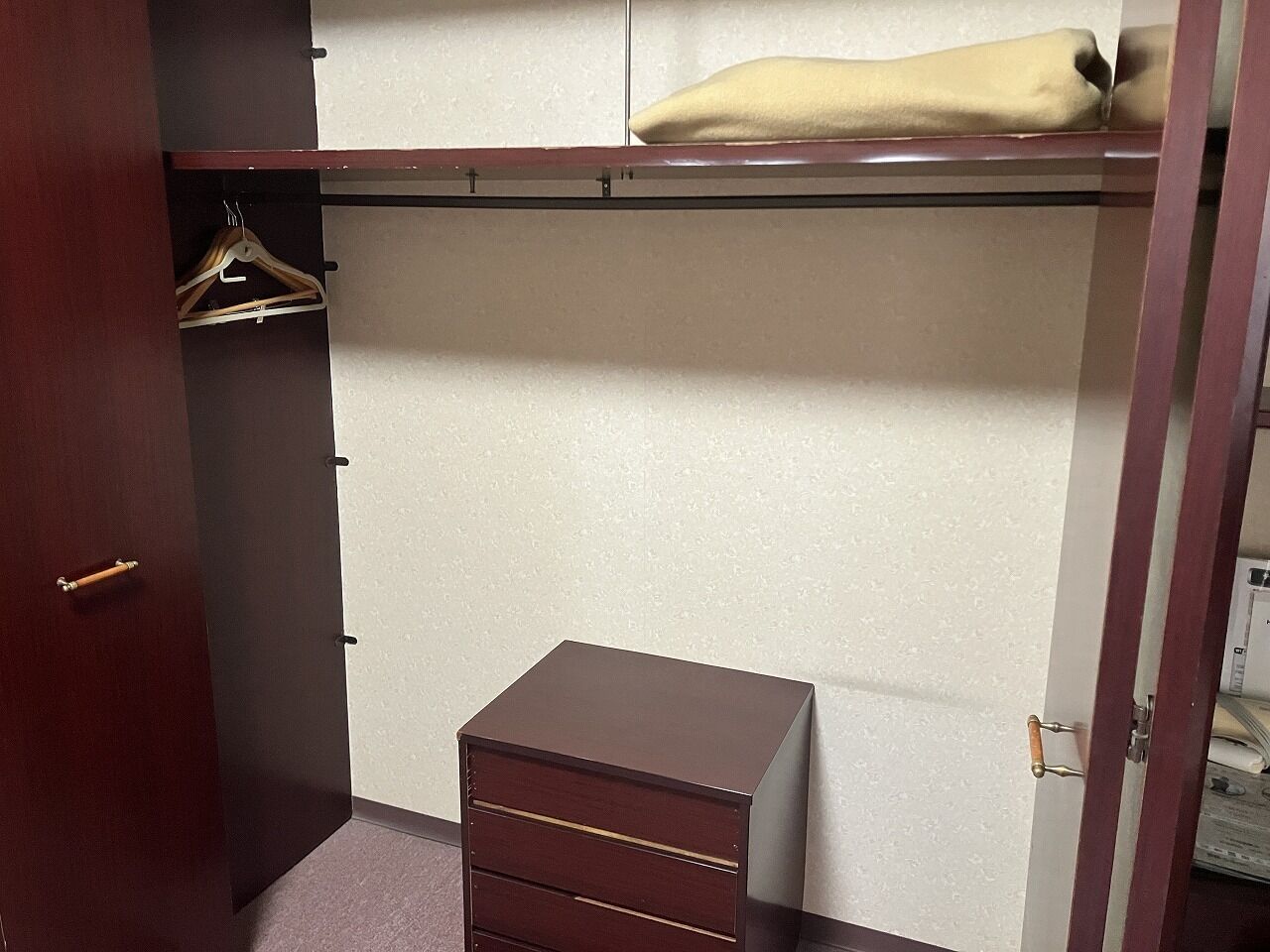 A bedroom with a bed, a wardrobe, and a small chest of drawers.