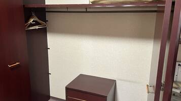 A bedroom with a bed, a wardrobe, and a small chest of drawers.