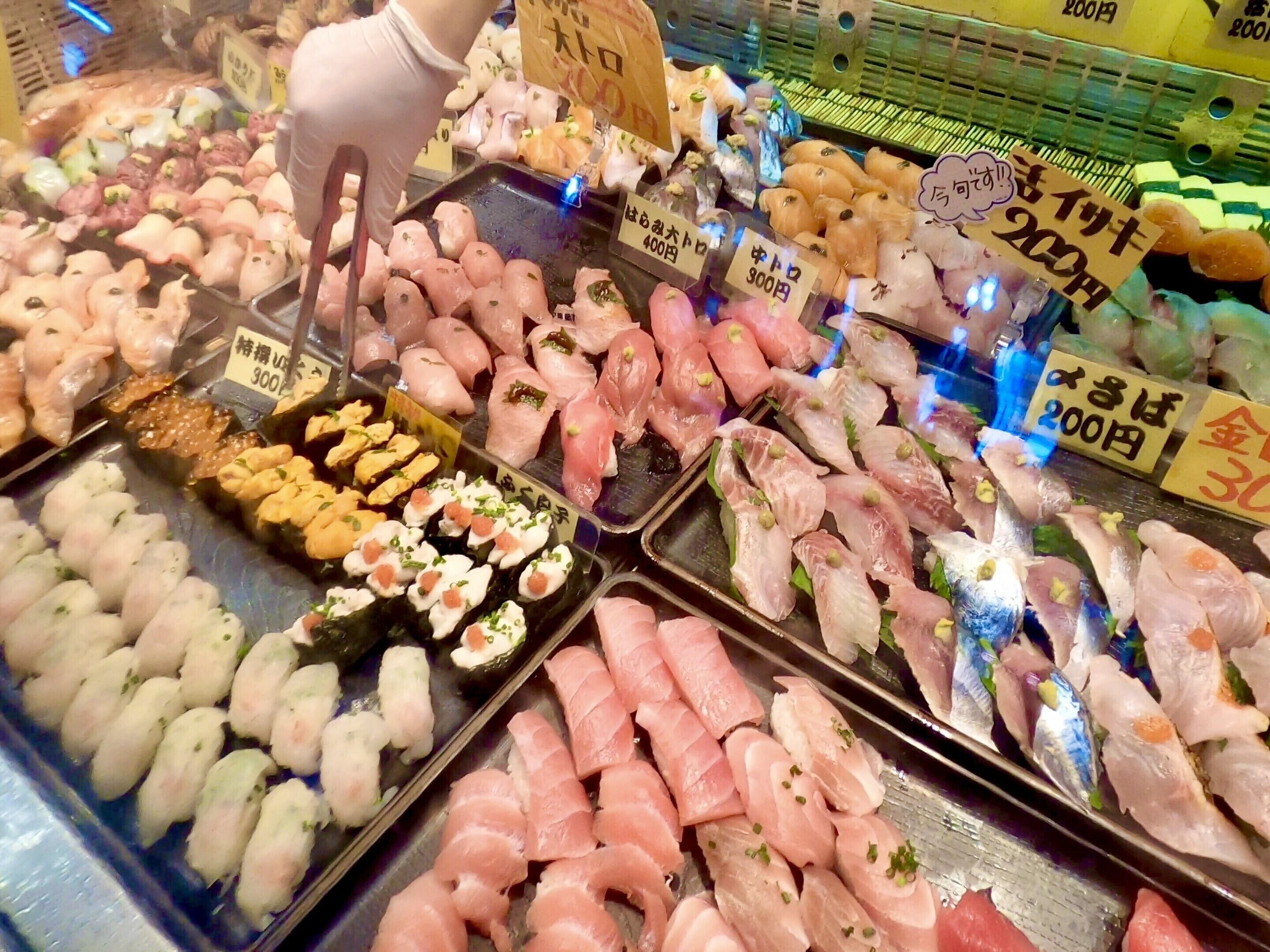 A variety of sushi displayed in a refrigerated case, with price tags visible.