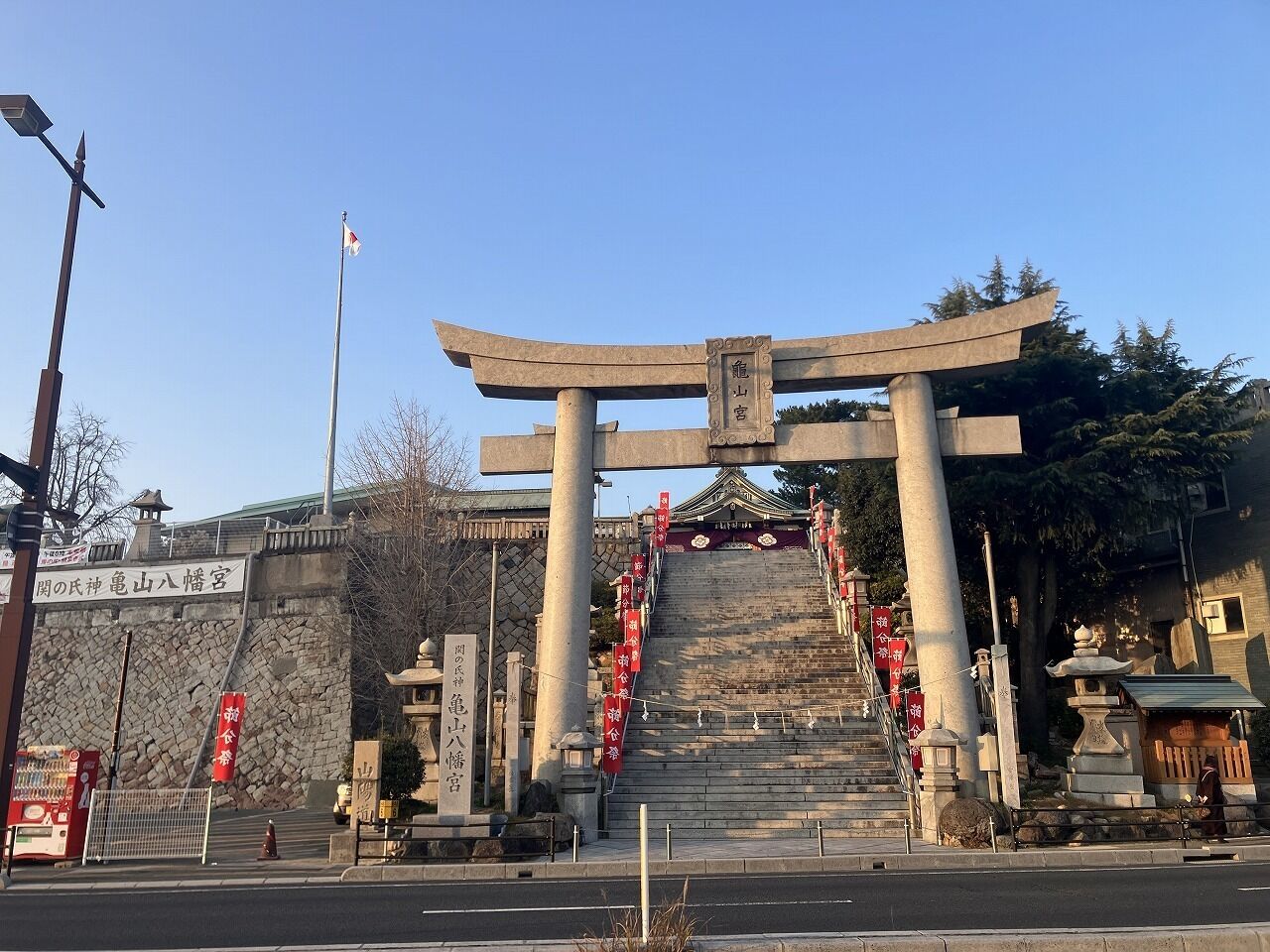 Un torii japonés tradicional con una escalera de piedra que conduce hacia él, rodeado de muros de piedra y un cielo despejado.