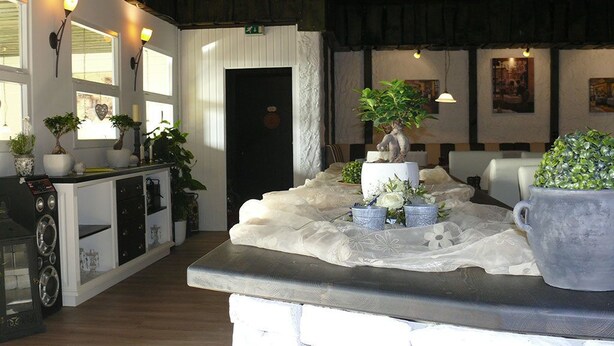 A cozy interior with a stone counter, potted plants, and a rustic wooden ceiling. - Hotel Restaurant Tüxen (Rendsburg)