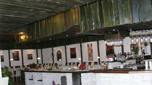 A restaurant with a rustic interior, featuring a stone counter, wooden beams, and framed pictures on the walls. - Hotel Restaurant Tüxen (Rendsburg)