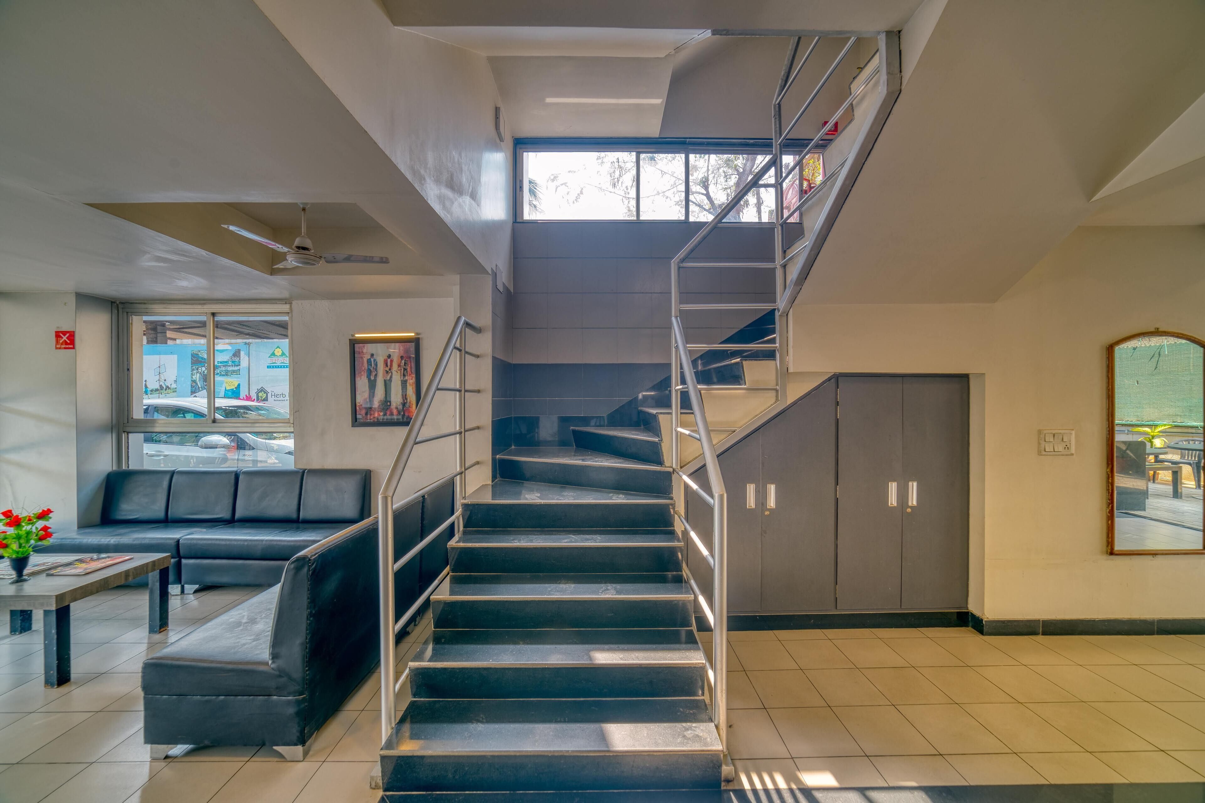 A staircase with metal railings, a black leather bench, and a tiled floor.