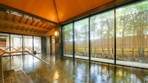 Un espacio interior amplio con piso húmedo, ventanas grandes y techo de madera.