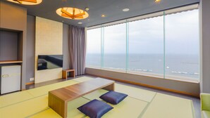 Una habitación moderna con un ventanal grande, un televisor de pantalla plana, una mesa de madera y esteras de tatami.
