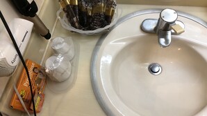 A bathroom sink with a faucet, a toothbrush holder, and a box of Propolis.