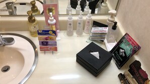 A bathroom sink with various toiletries and a tissue box.