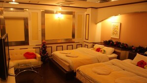 A hotel room with two beds, a small sofa, a Christmas tree, and a decorative garland.