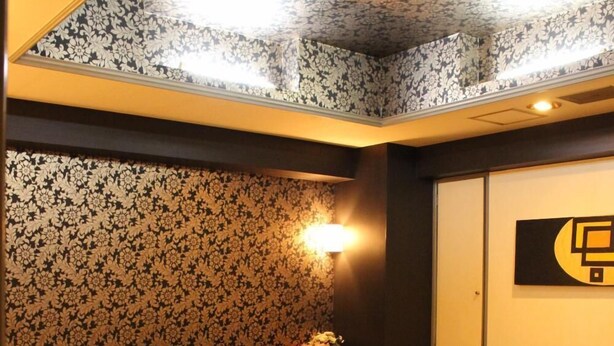 A hotel room with a large bed, a small sofa, a coffee table, and a wall-mounted TV.