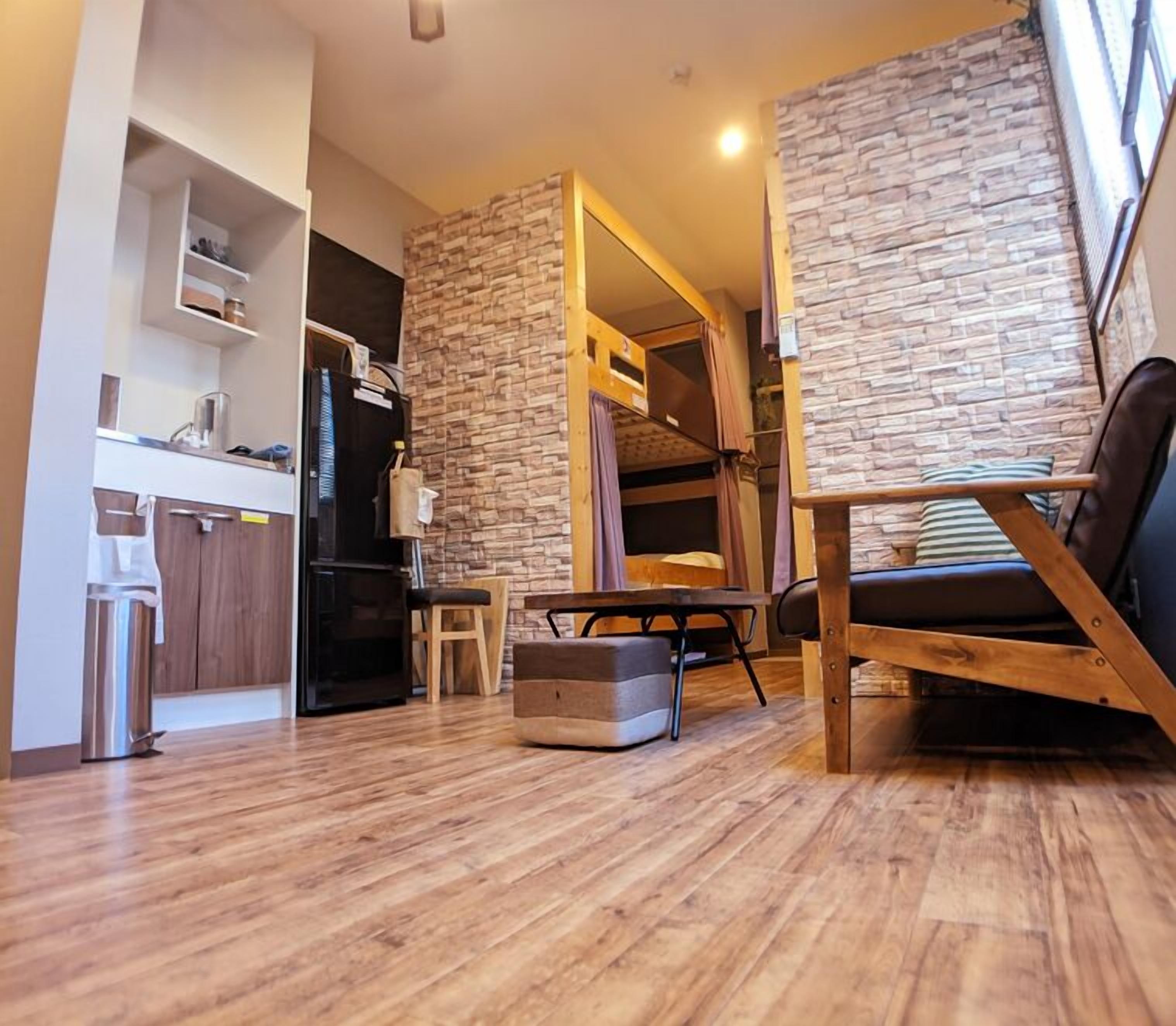 Un salon moderne comprenant un canapé, une table à manger et un coin cuisine avec des placards et un réfrigérateur.
