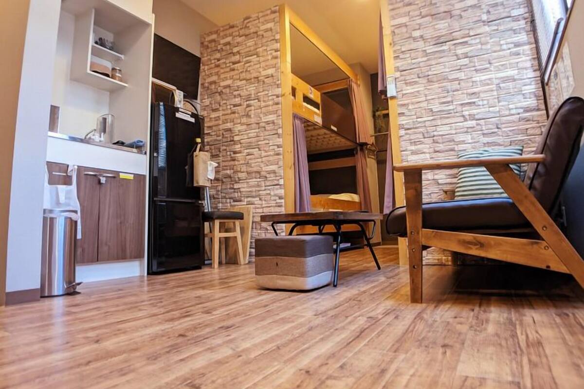 Un salon moderne comprenant un canapé, une table à manger et un coin cuisine avec des placards et un réfrigérateur.