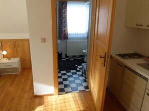 A small kitchen with wooden cabinets, a sink, and a checkered floor.