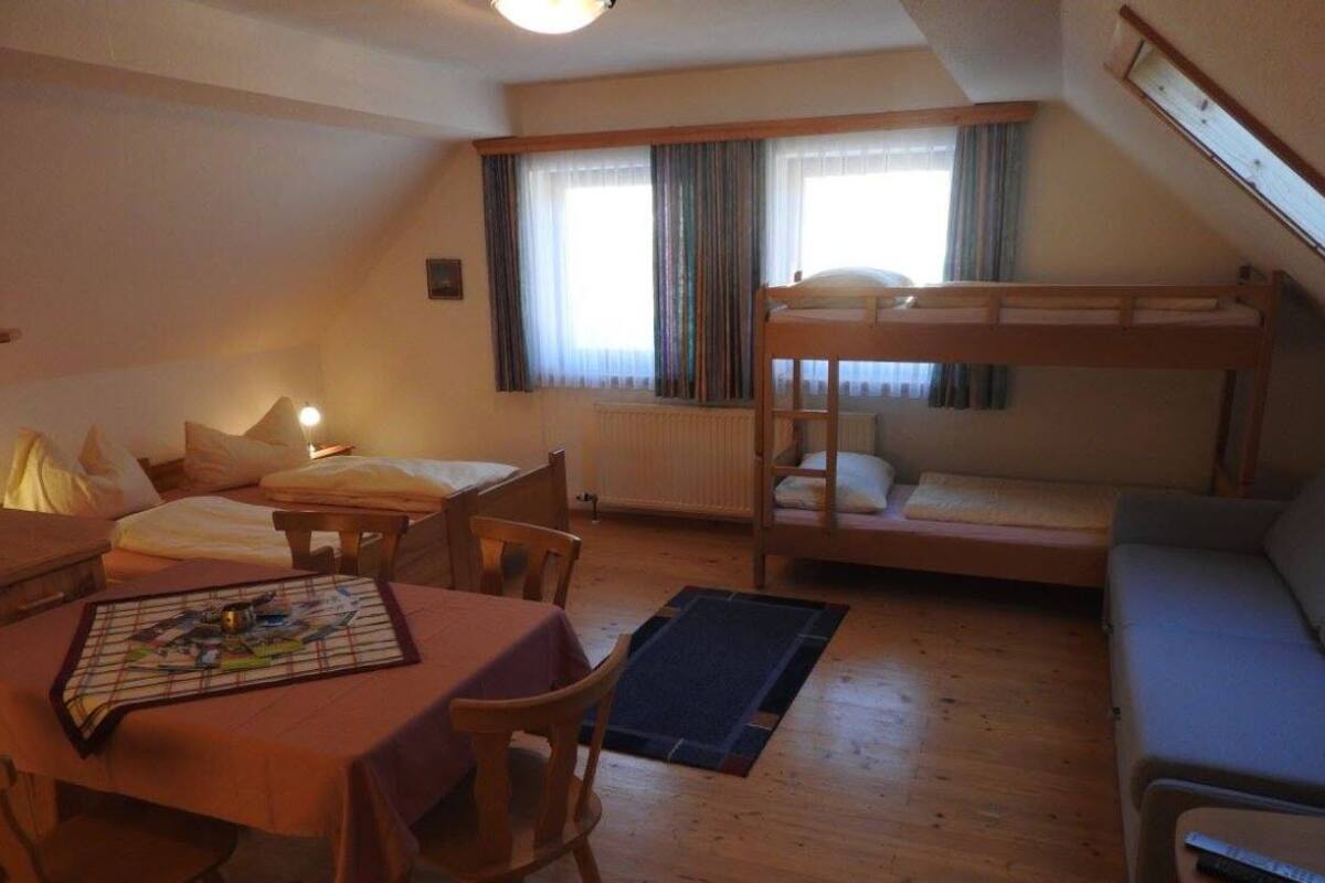 Una habitación acogedora con una cama litera, una mesa de comedor con sillas y un pequeño sofá.