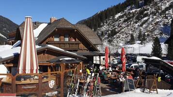 Eine Holzhütte mit einem Ski-Hang im Hintergrund.